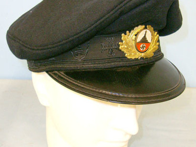 original manufacturer’s label printed in red on a clear cellophane panel togethe Alte Kameraden (Old Comrades) Dark Blue Cloth Visored Cap With Manufacturer’s La Clothing