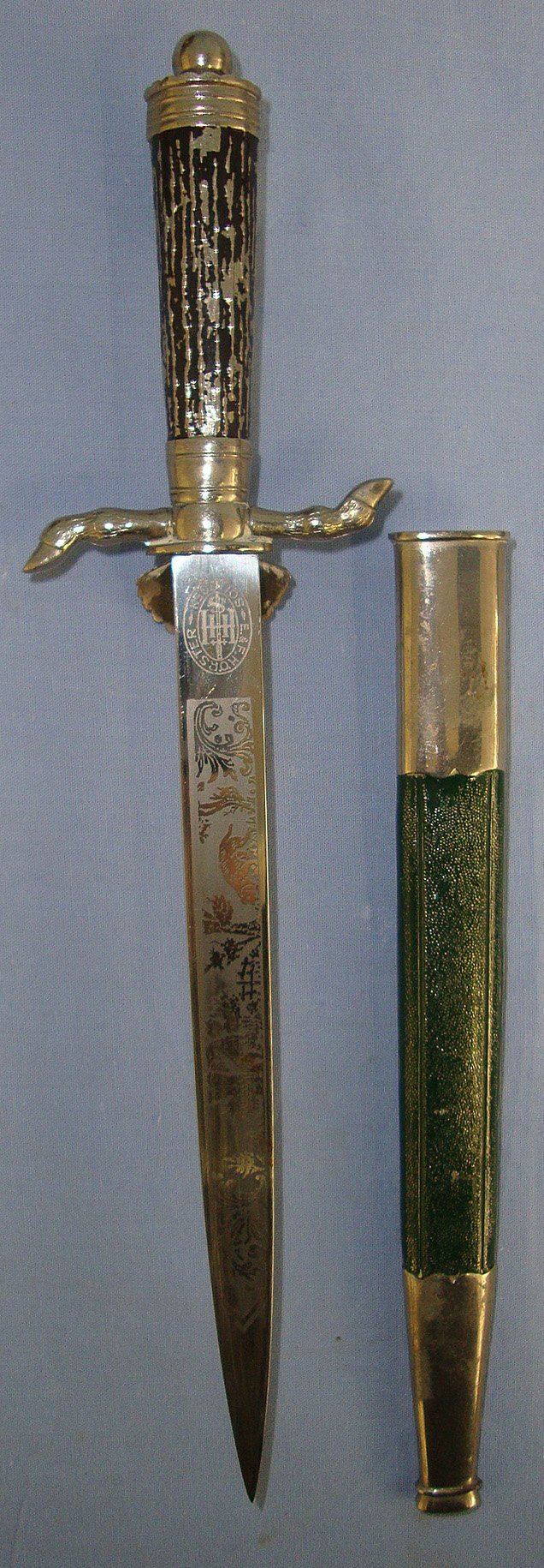 1934 – 1945 WW2 Era Nazi German Deutsche Jägerschaft (German Hunting Society) Badged, E&F Horster Solingen Miniature Clamshell Stag Hunting Dagger / Dirk With Hunting Scenes Blued & Etched Blade, Cast Alloy Hilt & Scabbard. Sn 23459  Dagger
