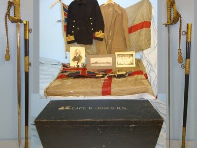 WW2 Era British Royal Navy Locker To Capt Jones DSO DSC HMS Walpole Containing A Collection Of Uniform, Dress Sword With Scabbard & Foul Weather Cover, 2 Large Ensign Flags & Ephemera. Sn 19345  Sword